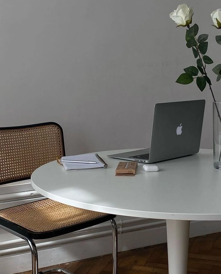 Minimal workspace with MacBook, notebook, pen, and white roses on a round table – freelance digital marketing expert in Calicut, Kerala.
